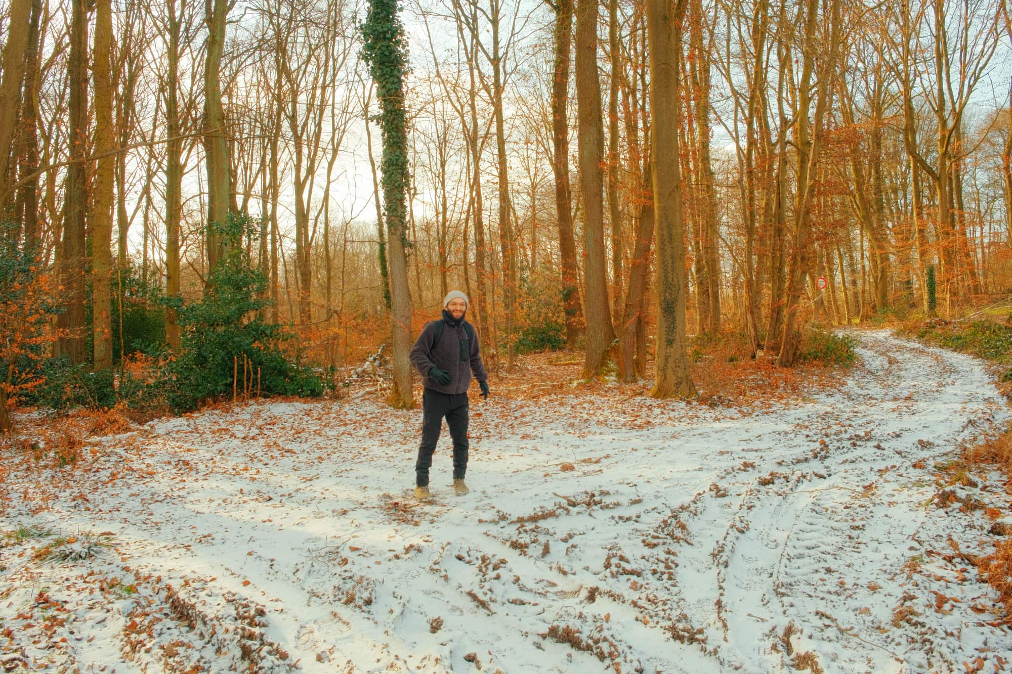 Authentischer Glatzenträger beim Digital Detox auf verschneitem Waldweg, natürliche Winterstimmung zwischen kahlen Bäumen symbolisiert Neuanfang