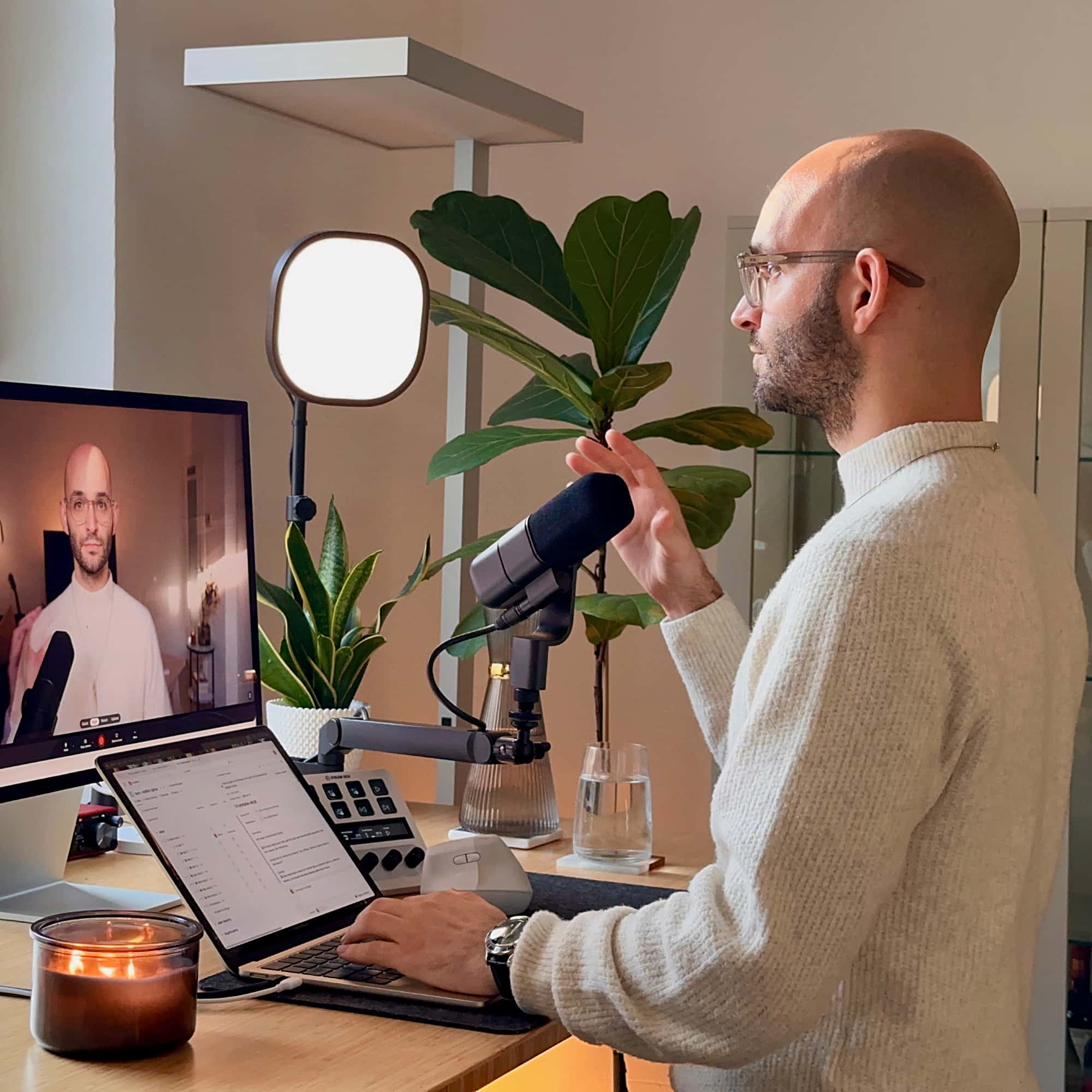 Professionelles Home-Office-Setup mit Mikrofon, Ringlight und Laptop. Mann mit Glatze nimmt Podcast oder Streaming-Content auf.