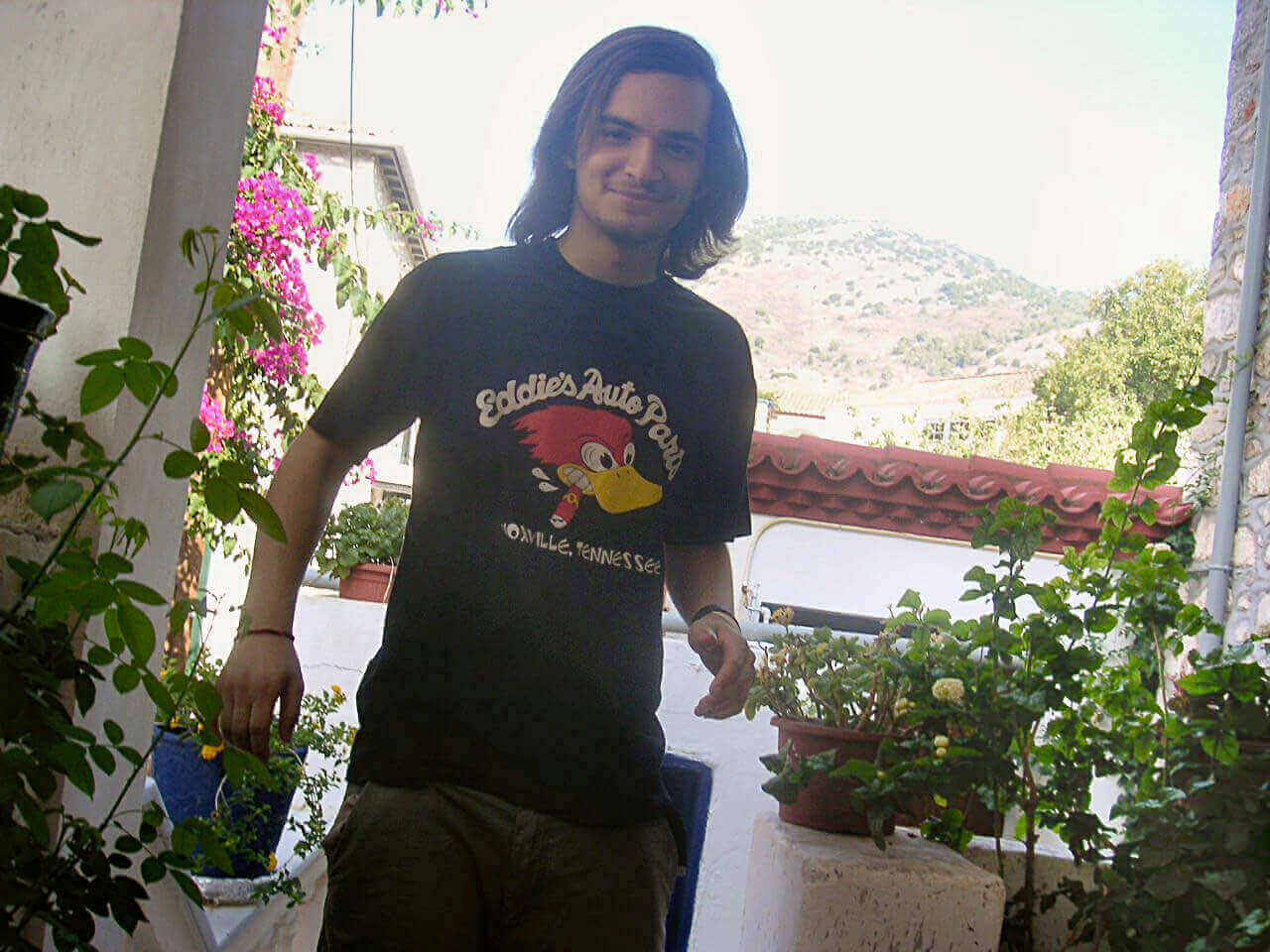 Junger Mann mit schulterlangen Haaren im Band-T-Shirt, Startpunkt der Glatze vorher nachher Transformation