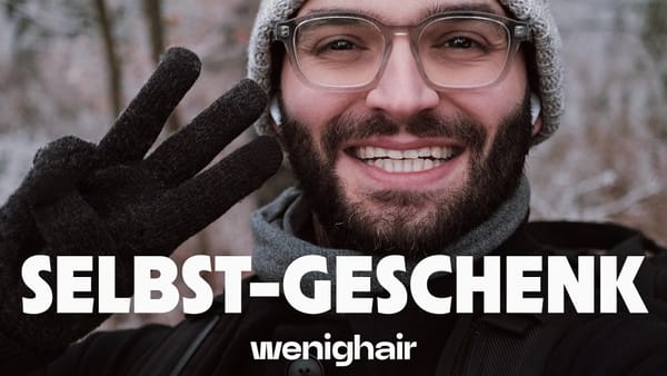 Winterliches Porträt mit “SELBST-GESCHENK” Schriftzug und wenighair Logo, lächelnder Mann mit Glatze zeigt wenighair-Zeichen